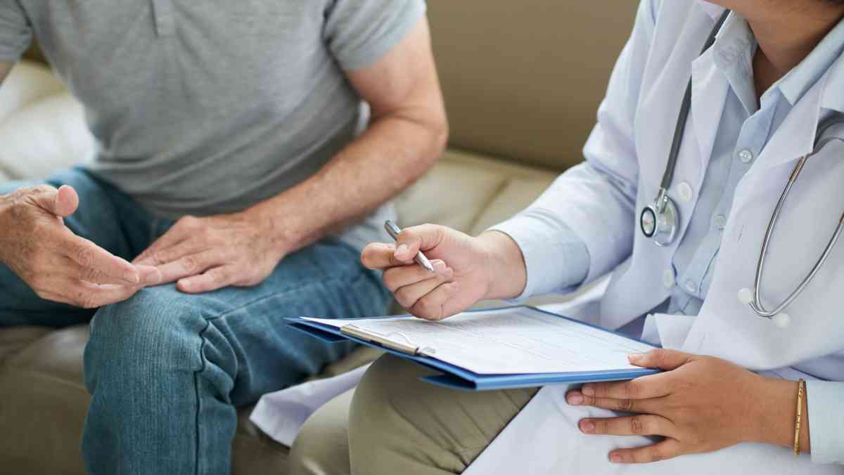 unrecognizable female doctor sitting couch with male patient filling form