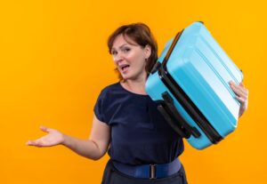 smiling middle aged traveler woman holding suitcase shoulder points with hand side 141793 72942