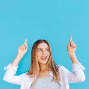 joyful young woman pointing her finger upward against blue background 23 2148178156