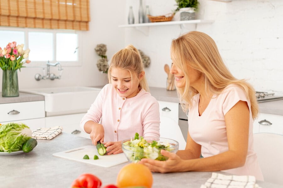 mother daughter cutting vegetables together 23 2148334844