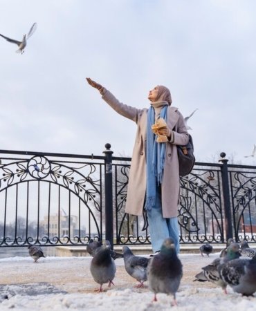 muslim-woman-feeding-pigeons-while-traveling-city_23-2149275774